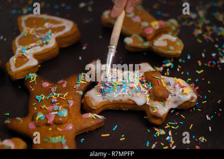 Boulangerie de Noël. Les amis de décorer des biscuits au gingembre avec du glaçage et de la confiserie mastic, vue de dessus. Repas de fête, la famille culi Banque D'Images