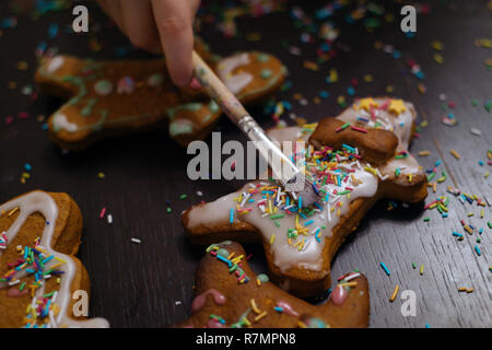 Boulangerie de Noël. Les amis de décorer des biscuits au gingembre avec du glaçage et de la confiserie mastic, vue de dessus. Repas de fête, la famille culi Banque D'Images