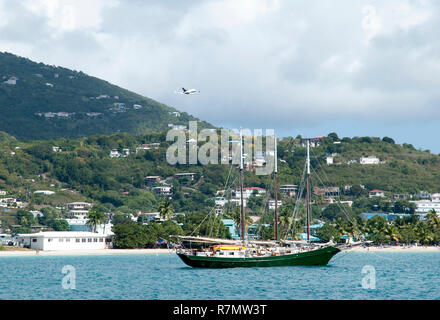 Le grand voilier dérive dans Lindbergh Bay alors que l'avion décolle de l'aéroport le plus proche (St. Thomas, îles Vierges américaines). Banque D'Images