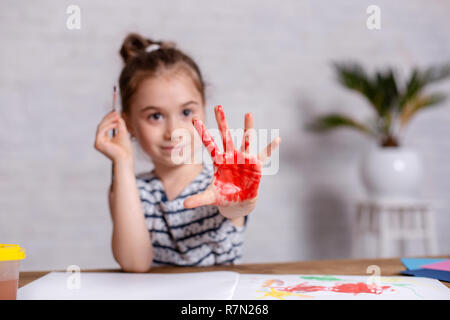 L'éducation, l'école, l'art et la peinture concept - smiling little girl étudiant à l'école montrant les mains peintes Banque D'Images