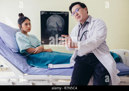 Le médecin est l'explication sur le cerveau le X-ray résultats à une femme au lit dans un hôpital Banque D'Images