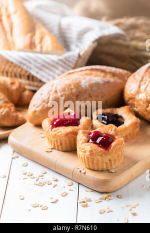 Du pain fait maison avec des fruits, danois de bleuets et de la sauce aux cerises sur fond de bois blanc, le petit déjeuner d'un concept top view et copy space Banque D'Images