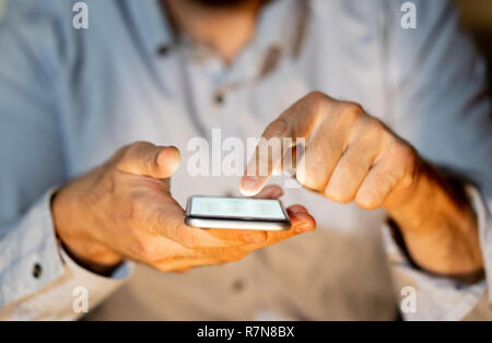 Close up of adolescent ou adulte homme jouant en ligne et l'envoi de texte sur smart phone avec un fond coloré la lumière de l'écran dans la toxicomanie Mobile Banque D'Images