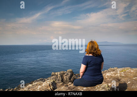 Red-haired woman looking out à la Petites Îles (Canna, Rum, Eigg et fumier) à partir de 38 Point. Banque D'Images