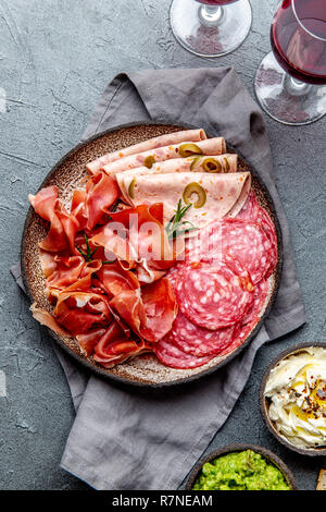 L'antipasto. Plateau de viande, frites et sauces, le vin rouge sur fond gris. Vue d'en haut Banque D'Images