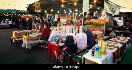 Voyage marrakech - touristes de manger des aliments de rue le soir à un blocage de l'alimentation en place Djemaa el Fna, Marrakech Maroc Sud Banque D'Images