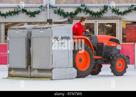 La préparation du patin à glace à la patinoire patinoire La cathédrale de Winchester, Winchester, Hampshire, Royaume-Uni en décembre - à l'aide de tracteur Kubota L3540 à refaire surface Banque D'Images