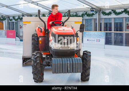 La préparation du patin à glace à la patinoire patinoire La cathédrale de Winchester, Winchester, Hampshire, Royaume-Uni en décembre - à l'aide de tracteur Kubota L3540 à refaire surface Banque D'Images