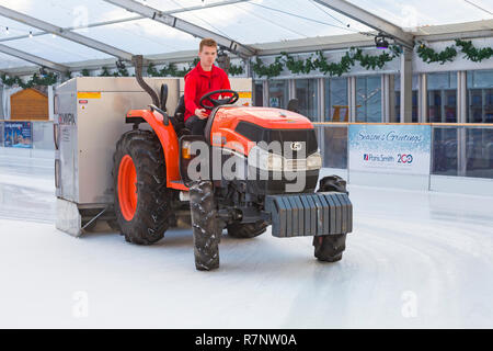 La préparation du patin à glace à la patinoire patinoire La cathédrale de Winchester, Winchester, Hampshire, Royaume-Uni en décembre - à l'aide de tracteur Kubota L3540 à refaire surface Banque D'Images