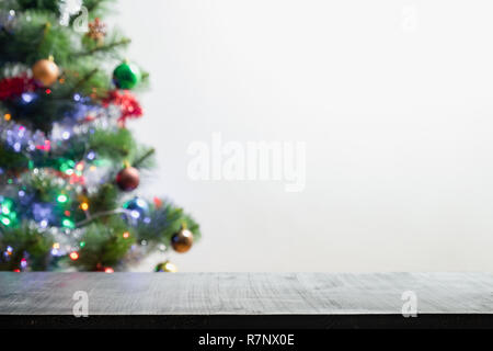 Produits de Noël avec sapin en arrière-plan flou. Tourné avant de table en bois noir rétroéclairé et des problèmes de mise au point de l'arbre de pin de guirlandes Banque D'Images