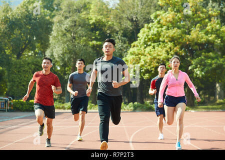 Groupe de jeunes hommes et femmes athlètes asiatiques formation ensemble sur la voie. Banque D'Images