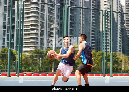 Deux jeunes joueurs de basket-ball asiatique jouant un sur une cour en plein air. Banque D'Images