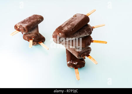 Glace au chocolat sur un fond bleu clair, sur un bâton de popsicle Banque D'Images