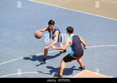 Deux jeunes joueurs de basket-ball asiatique jouant un sur une cour en plein air. Banque D'Images