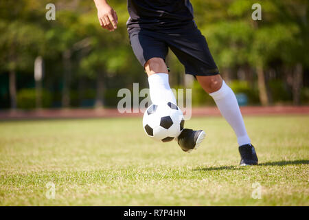 Close-up shot de pieds de joueur de football asiatique de la manipulation du ballon sur terrain de football. Banque D'Images