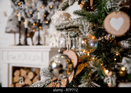 L'intérieur classique d'une chambre blanche avec une cheminée décorée, arbre de Noël, des guirlandes, des bougies, des lanternes, des cadeaux dans le matin.Belle décoration Nouvel An home intérieur. Fond d'hiver.Les jouets en bois Banque D'Images