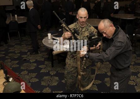 Le sergent d'artillerie du Corps des Marines des États-Unis. Freddie Herrin, gauche, l'équipe de réaction spéciale (SRT) Le commandant de Marine Corps Air Station (MCAS Iwakuni), montre des armes utilisées par SRT à un membre de la Police de la préfecture de Yamaguchi, siège de droite, au MCAS Iwakuni, Japon, le 28 mars 2017. Membres l'Hiroshima et le quartier général de la Police de la préfecture de Yamaguchi s'est rendu à la station aérienne d'observer la conduite de la TRR des scénarios de formation à haut risque. La formation variait de prix-compensation, de violer, de la communication et non létales techniques de retrait. Banque D'Images