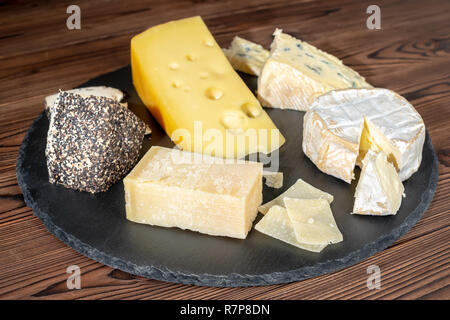 Divers types de fromages délicieux sur fond noir en ardoise Banque D'Images