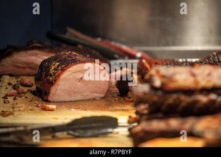 Canadian Bacon, également connu sous le peameal, à la vente, grillé et cuit, être prêt à couper sur une planche en bois, entourée d'autres viandes cuites. Pictu Banque D'Images