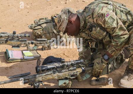 Un formateur britanniques déployées à l'appui de la Force opérationnelle interarmées - Fonctionnement résoudre inhérent et affecté à l'Highlanders, 4e Bataillon, The Royal Regiment of Scotland (4) charge un Écossais dans son magazine L115A3 fusil de sniper à longue portée pendant la formation à Al Asad Air Base, l'Iraq, le 21 mars 2017. Cette formation fait partie de l'ensemble de la CJTF OIR - renforcer les capacités des partenaires mission par la formation et de l'amélioration de la capacité des forces des combats en partenariat avec ISIS. Les GFIM - OIR est la Coalition mondiale pour vaincre ISIS en Iraq et en Syrie. Banque D'Images