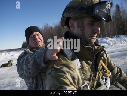 Le sergent de l'armée américaine. Robert Osborne, gauche, inspecte le sergent de l'Armée de l'air. Dylan parachute du Shimamura-Welch pack avant de faire des sauts d'hélicoptère à la formation sur la zone de largage Malemute Joint Base Elmendorf-Richardson, Alaska, le 22 mars 2017. Osborne est un cours d'arrimeurs affectés à la 4e compagnie de quartier-maître, 725e Bataillon de soutien de Brigade (Airborne), et Shimamura-Welch est un spécialiste de l'air de contrôle tactique partie affecté à la 3e escadron des opérations d'appui aérien. La Garde nationale de l'Alaska 1er bataillon du 207e Régiment d'aviation, a fourni des hélicoptères UH-60 Black Hawk pour soutenir le saut Banque D'Images