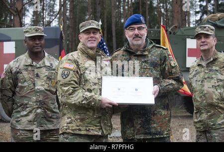 GRAFENWOEHR, Allemagne - Le Général de brigade de l'armée américaine Steven Ainsworth (centre gauche), général commandant adjoint du 21e Commandement de soutien de théâtre, serre la main avec le Major général Ulrich Baumgartner (centre droit), général commandant de la Bundeswehr, Commandement du soutien médical opérationnel après la signature du premier protocole de partenariat entre les deux unités au cours d'une Europe de l'Armée américaine sur le terrain de l'évaluation d'experts médicaux d'un insigne à Grafenwoehr, Allemagne le 24 mars 2017. Environ 215 candidats de l'armée américaine et européenne de dix pays partenaires ont participé à l'évaluation semestrielle dans l'espoir o Banque D'Images