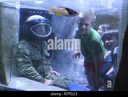 AUSTIN, Texas (23 mars 2017) l'élimination des explosifs et munitions de 1ère classe technicien Seth Willey, affecté à l'unité mobile de destruction des engins explosifs (EODMU) 11, interagit avec les enfants tout en portant un casque de bombes à l'Aquarium pendant la Semaine de la Marine Austin Austin. Les programmes de la Semaine de la marine servent de l'effort principal de la Marine de sensibilisation dans les régions du pays sans une importante présence de la Marine. Banque D'Images