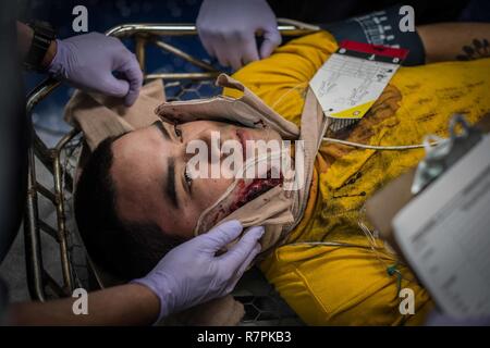 SAN DIEGO (Mar. 24, 2017) marins traiter une victime de traumatisme théorique avec une lacération au visage lors d'une évolution de la formation de nombreux blessés à bord du porte-avions USS Theodore Roosevelt (CVN 71). Le navire est amarré et homeported au Naval Air Station North Island. Banque D'Images