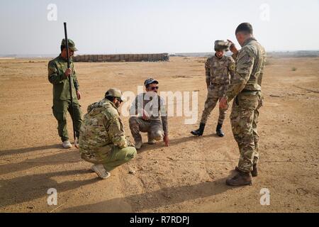 Un entraîneur britannique, déployées à l'appui de la Force opérationnelle interarmées - Fonctionnement, explique à résoudre inhérent aux forces de sécurité iraquiennes soldats la façon de détecter un engin explosif sur une patrouille au cours de la lutte contre les IED à Al Asad Air Base, l'Iraq, le 29 mars 2017. Cette formation fait partie de l'ensemble de la FOIC- OIR renforcer les capacités des partenaires mission par la formation et de l'amélioration de la capacité des forces des combats en partenariat avec ISIS. Les GFIM- OIR est la Coalition mondiale pour vaincre ISIS en Iraq et en Syrie. Banque D'Images