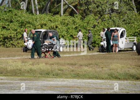 L'équipage de la Garde côtière canadienne d'aider le personnel des services d'urgence locaux dans le transport d'un patient à Queens Medical Centre à partir de la Coast Guard Air Station barbiers Point, Oahu, le 4 avril 2017. Le 74-year-old man est arrivé dans un état stable à Honolulu après avoir été évacué par un HC-130 Hercules avion à voilure fixe 1 061 miles de Atoll de Palmyra. Banque D'Images