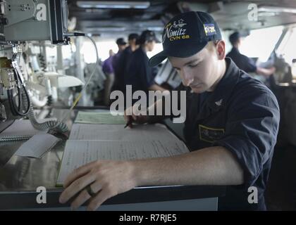 Océan Pacifique (31 mars 2017) Maître de Manœuvre 3 classe Eric Hunt, attribué à le porte-avions USS Nimitz (CVN 68), examine le journal de bord du navire, avant de faire une entrée tout en en cours. Nimitz est en cours la réalisation d'une unité de formation composite de l'exercice avec le groupe c'est en préparation pour un prochain déploiement. Banque D'Images