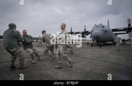 Le lieutenant-colonel Bernabe F. Whitfield, commandant adjoint du groupe de maintenance 374, cheers une équipe sur comme ils tirent un C-130H Hercules sur la piste pendant la 374e Groupe Wrenchbender Entretien Rodeo 31 mars 2017, à Yokota Air Base, le Japon. Des équipes des différents escadrons de maintenance se faisaient concurrence dans 9 événements, dont : 4-man push-ups, véhicule push, les yeux bandés, l'accumulation de la boîte à outils du relais d'entretien, barre de remorquage, d'identification de l'outil de leadership, caler tenez, Self-Aid et Buddy relais Soins et fini avec un C-130 tirer. Banque D'Images