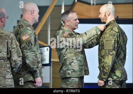 L'ARMÉE AMÉRICAINE L'Europe Général Commandant adjoint, Brig. Le général Phillip S. Jolly, centre, prix l'expert médical de terrain (EFMB Badge) à un soldat, République Chèque, droit au cours de l'EFMB cérémonie de remise des prix au 7e commandement de l'instruction de l'armée, Grafenwoehr, Allemagne, le 30 mars, 2017. 215 candidats de 11 pays, s'efforcer de l'insigne au cours des cinq jours de défi. L'EFMB renforce la concurrence des compétences individuelles des soldats et renforce les liens avec les alliés et partenaires. Banque D'Images