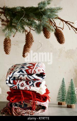 Une pile de vêtements chauds sur la table. Ambiance de Noël à la Chambre. Salle décorée de branches de sapin avec les cônes. Style de vie. Automne ou hiver stil Banque D'Images