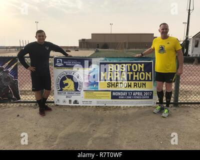 1er lieutenant Jared Pyland (gauche), pose avec Douglas Flannery, directeur de course de la paix Boston Athletic Association et Marathon de Boston, avec une bannière annonçant le Marathon de Boston Shadow Run, qui a eu lieu, le 17 avril 2017, Camp Arifjan, au Koweït. Banque D'Images