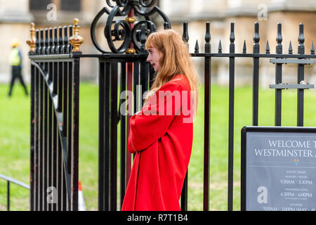 Londres, Royaume-Uni - 12 septembre 2018 : personnes usher femme debout par porte d'entrée à l'abbaye de Westminster, bâtiment de l'église tour libre, wearing red coat Banque D'Images