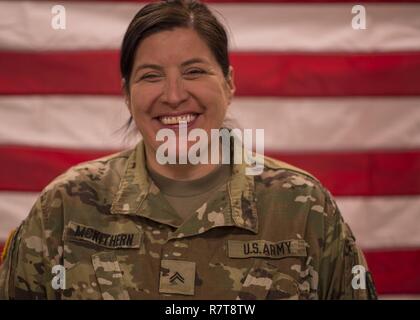 Réserve de l'armée américaine le Cpl. McKithern Tracy, un photographe avec Det. 5, 982e Caméra Combat Co. (aéroportée) à partir de San Antonio, Texas, pose devant un drapeau américain avant son déploiement cérémonie à la 335e commande de signal (Théâtre) à East Point, Géorgie, le 7 mars 2017. Le détachement a été de se lancer dans un déploiement de neuf mois pour le Moyen-Orient à l'appui de la Force Opérationnelle Interarmées OIR. Banque D'Images