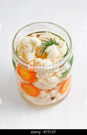 Au-dessus du coup de pot ouvert de chou-fleur fermenté avec de l'aneth et carotte standingon fond blanc Banque D'Images