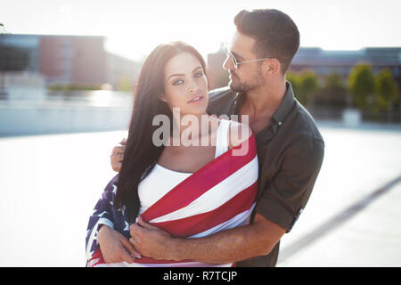 Jeunes trendy man embracing belle petite amie avec USA flag, le bonheur Banque D'Images