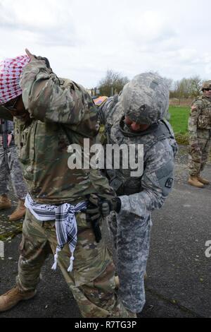 Des soldats américains affectés au 39e Bataillon du signal, trouve une arme sur le suspect lors de l'entrée de la recherche du point de contrôle de l'exercice, commandant de la Base Aérienne de Chièvres, Belgique, le 21 mars 2017. Banque D'Images