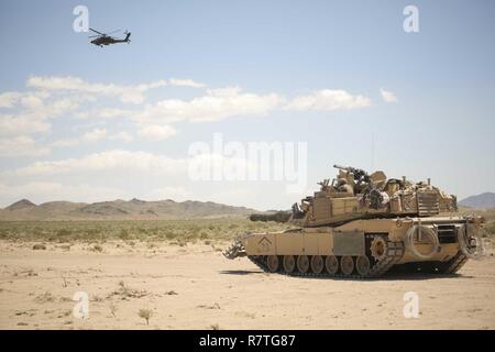 Des soldats américains dans un hélicoptère d'attaque AH-64 Apache, affecté à la 1ère Brigade Combat Team, 3e Division d'infanterie, voler au-delà d'un réservoir d'Abrams, au cours de l'action décisive 17-05 Rotation au Centre National d'entraînement à Fort Irwin, en Californie, Avril 03, 2017. Banque D'Images