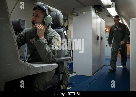 U.S. Air Force d'un membre de la 1re classe Favian Arteaga, 961e Airborne Air Control Squadron technicien de surveillance aéroporté (à gauche), utilise un système de communication le 28 mars 2017, alors qu'il volait dans un E-3 Sentry sur l'océan Pacifique. La surveillance aérienne des techniciens effectuent l'identification initiale des Ami ou ennemi des avions et de surveiller leur position. Banque D'Images