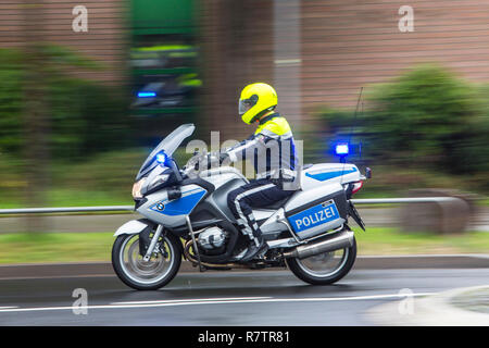 Policier portant un casque jaune sur une moto, moto de police patrouille de la police NRW équitation avec feux bleus scintillants Banque D'Images