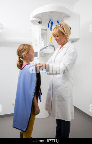 Girl en cours de préparation pour une radiographie de ses dents, portant un gilet de plomb que la protection contre les rayonnements ionisants, Allemagne Banque D'Images