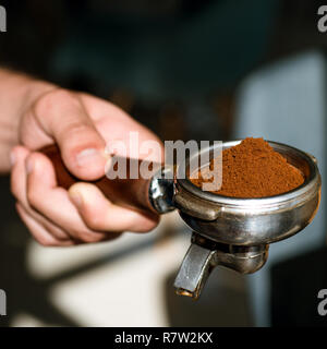 Aroma afin de lancer et de dynamiser votre journée. Brews Barista espresso coffee dans le café. Café au café Le café de l'équipement. Café frais moulu. Tenir en main portafilter Barista Banque D'Images