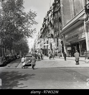 1950s, voitures historiques garées et personnes sur une petite rue à côté des champs-Elysées, une avenue historique dans le centre de Paris, France. Le boulevard phare va entre la place de la Concorde à l'est et la place Charles de Gaulle à l'ouest, où se trouve le célèbre Arc de Triomphe. Banque D'Images