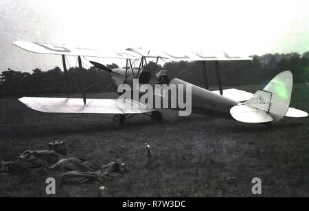 Années 1950, histoirical, garé dans un champ, un biplan, un 2 places, le Tiger Moth habitacle ouvert et transmettre ce aeoplane (non G-ACEZ) faites par de Haviilland dans les années 1930 et principalement utilisé comme un avion d'entraînement. Probablement le meilleur avion de formation connu, plus de 9 000 Tiger Moth ont été construites. Banque D'Images