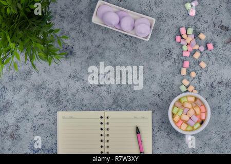 Tasse à café et les guimauves, vierge ouvrir bloc-notes avec stylo sur résumé fond bleu. Vue d'en haut. Télévision immersive. espace pour texte. Banque D'Images