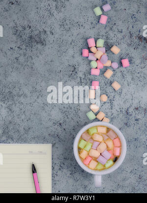 Tasse à café et les guimauves, vierge ouvrir bloc-notes avec stylo sur résumé fond bleu. Vue d'en haut. Télévision immersive. espace pour texte. Banque D'Images