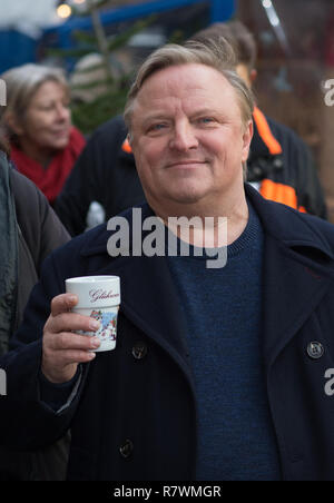 Symbole - 11 décembre 2018, en Rhénanie du Nord-Westphalie, Münster : l'acteur Axel Prahl comme le commissaire Frank Thiel est titulaire d'une tasse de vin chaud au marché de Noël au cours d'une séance photo pour la nouvelle scène de crime WDR 'Dann steht der Mörder vor der Tür". Photo : Friso Gentsch/dpa Banque D'Images